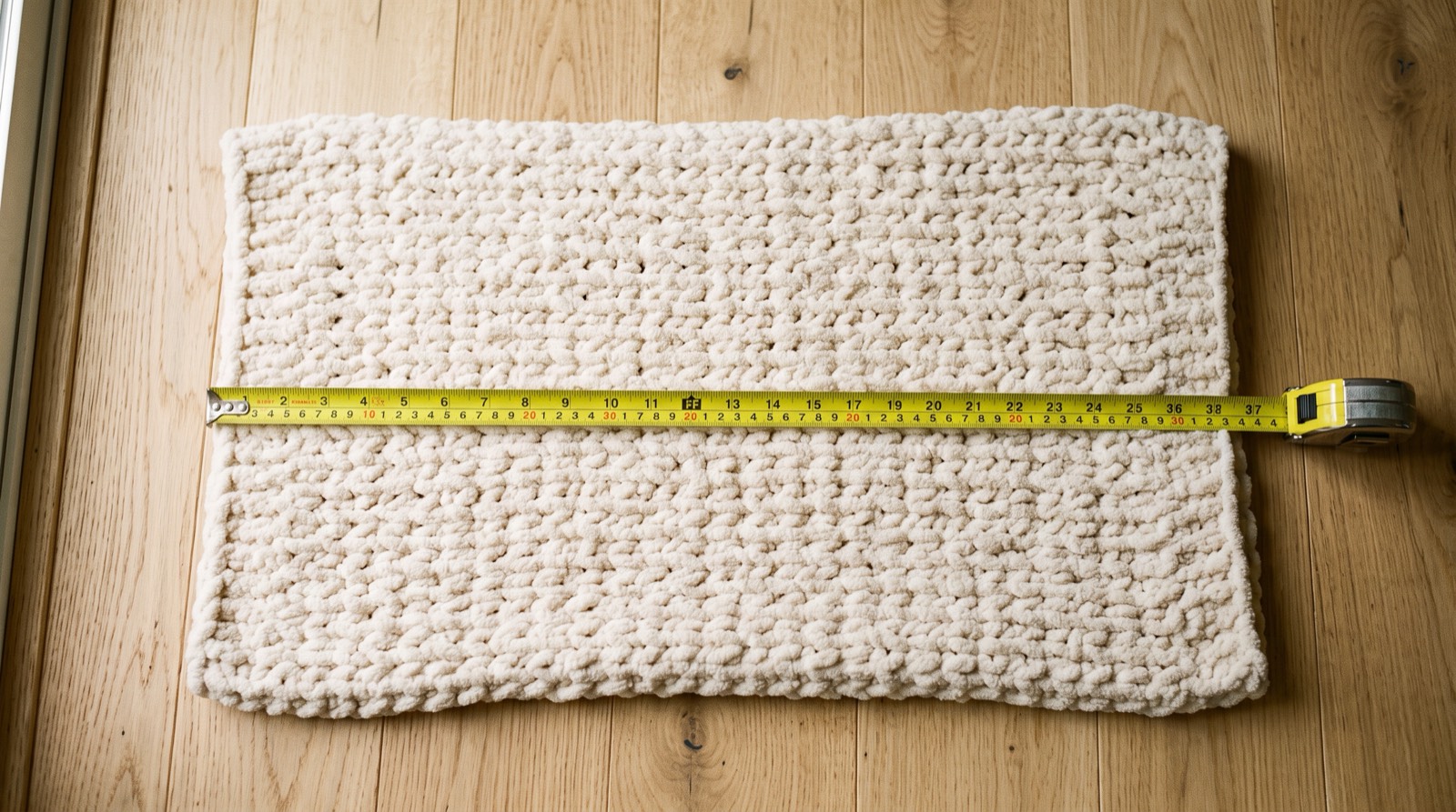 finished chunky chenille blanket measured with a tape measure on a wood floor
